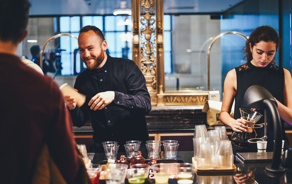man and woman serving up coffees and drinks inside 
