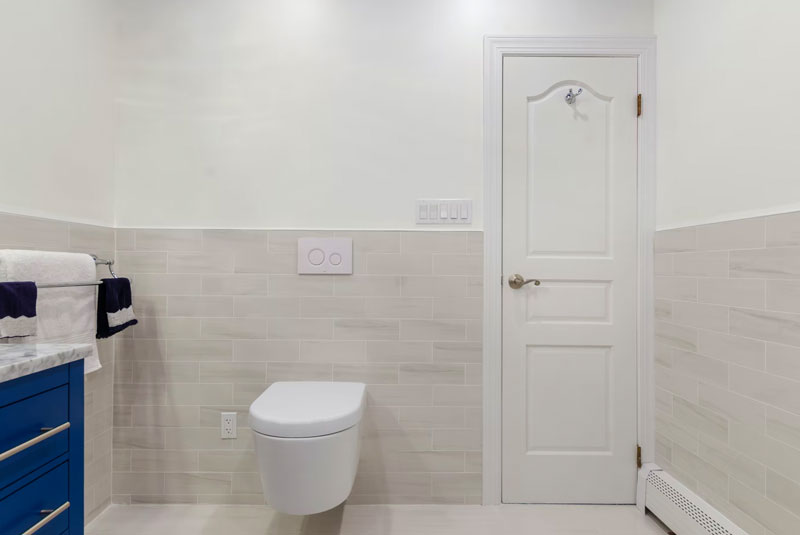 white bathroom with closed floor and to the right is a toilet seat with the lid down