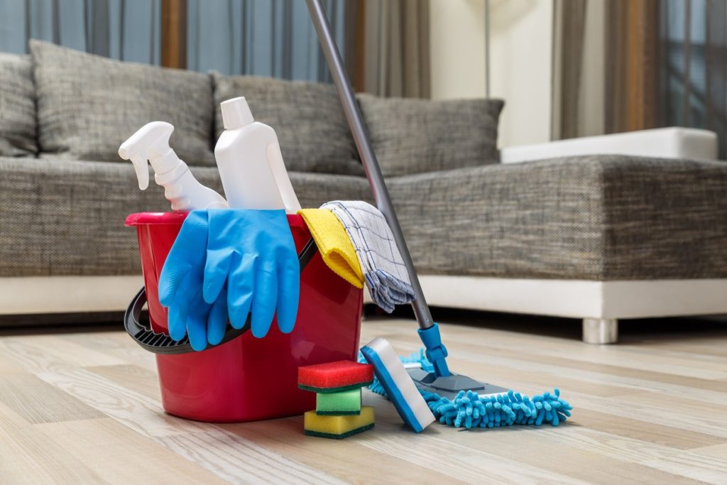 Bucket with sponges, chemicals bottles and mopping stick. Rubber gloves and towel. Household equipment.