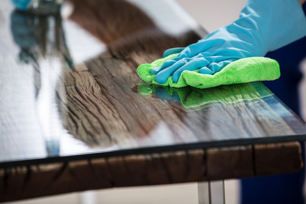 Close-up Of A Janitor's Hand Wearing Gloves Cleaning Desk With Green Cloth